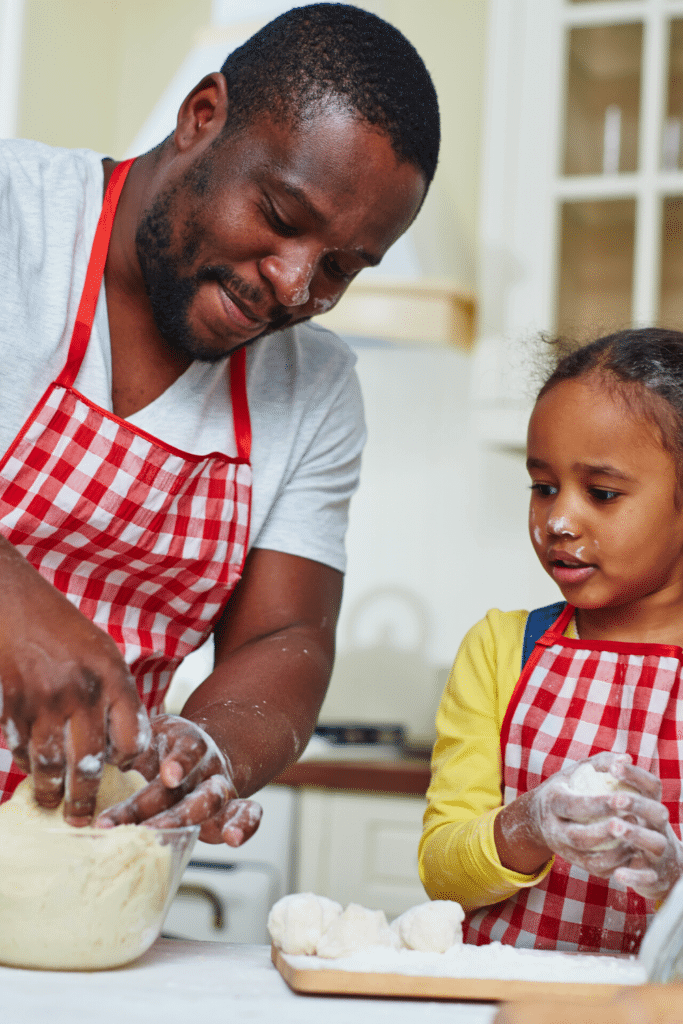 a father and daughter with printed aprons cook in the kitchen