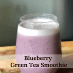 A purple smoothie in a short glass with spinach and blueberries as garnish