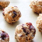 oatmeal colored balls on parchment with bright raisins embedded