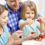 a family cooking together with kids hulling strawberries