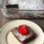 perfectly baked brownies with a strawberry and powdered sugar on top