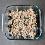dark blackberries and a golden oat topping in a glass dish