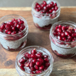 vibrant, crimson pomegranate arils on top of creamy chia seed pudding in mini mason jars